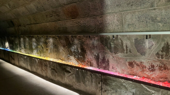 A long, narrow shelf on a stone wall is holding something colourful.