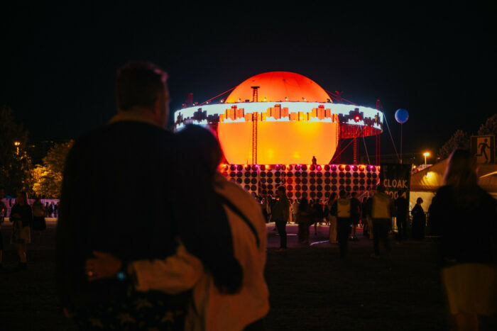 A large sphere above a stage area glows orange in the nighttime.