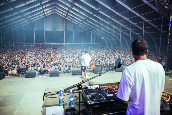 Um homem está na frente do palco diante de uma plateia que preenche um vasto salão.