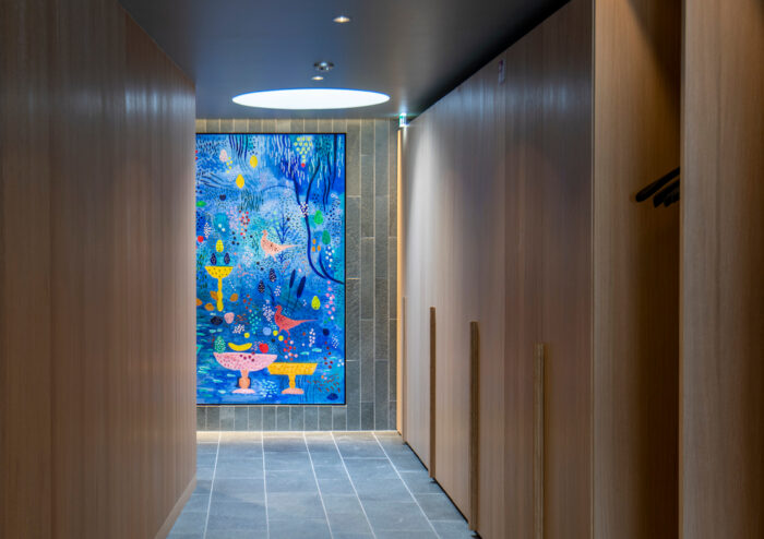 在木板墙走廊的尽头，可以看到一幅色彩斑斓的鸟类主题画作。