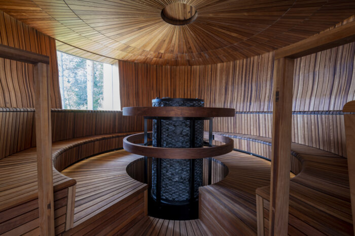 Uma sauna redonda com painéis de madeira e um forno no meio.