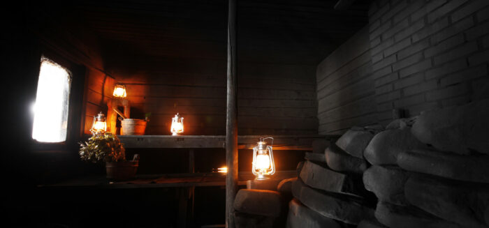 Several lanterns decorate the benches of a sauna room with a window on one side.