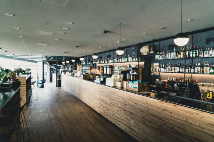 Una imagen del interior de un restaurante decorado en madera, con varias mesas a lo largo de una larga barra.