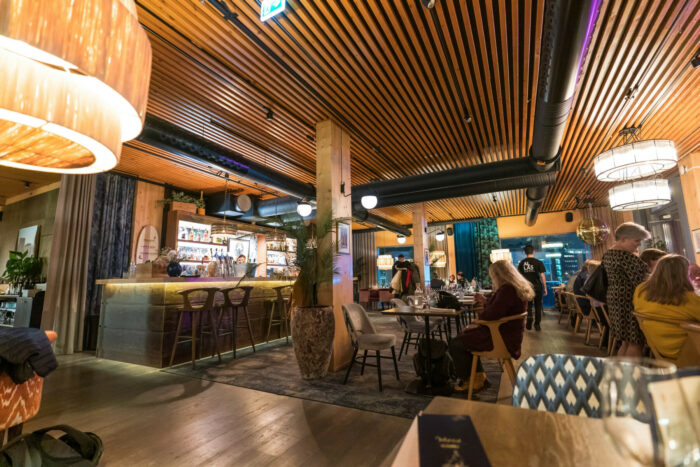 On voit un restaurant au décor chaleureux dont les sols et les meubles sont en bois.