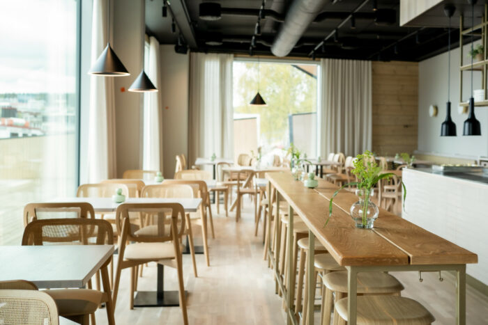 Mesas de restaurante são colocadas ao lado de uma janela que vai do chão ao teto.