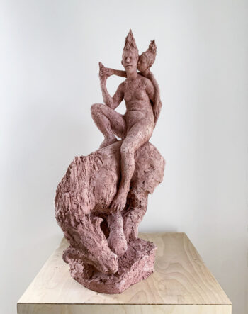 Una escultura con dos figuras humanas a lomos de un animal parecido a un caballo.