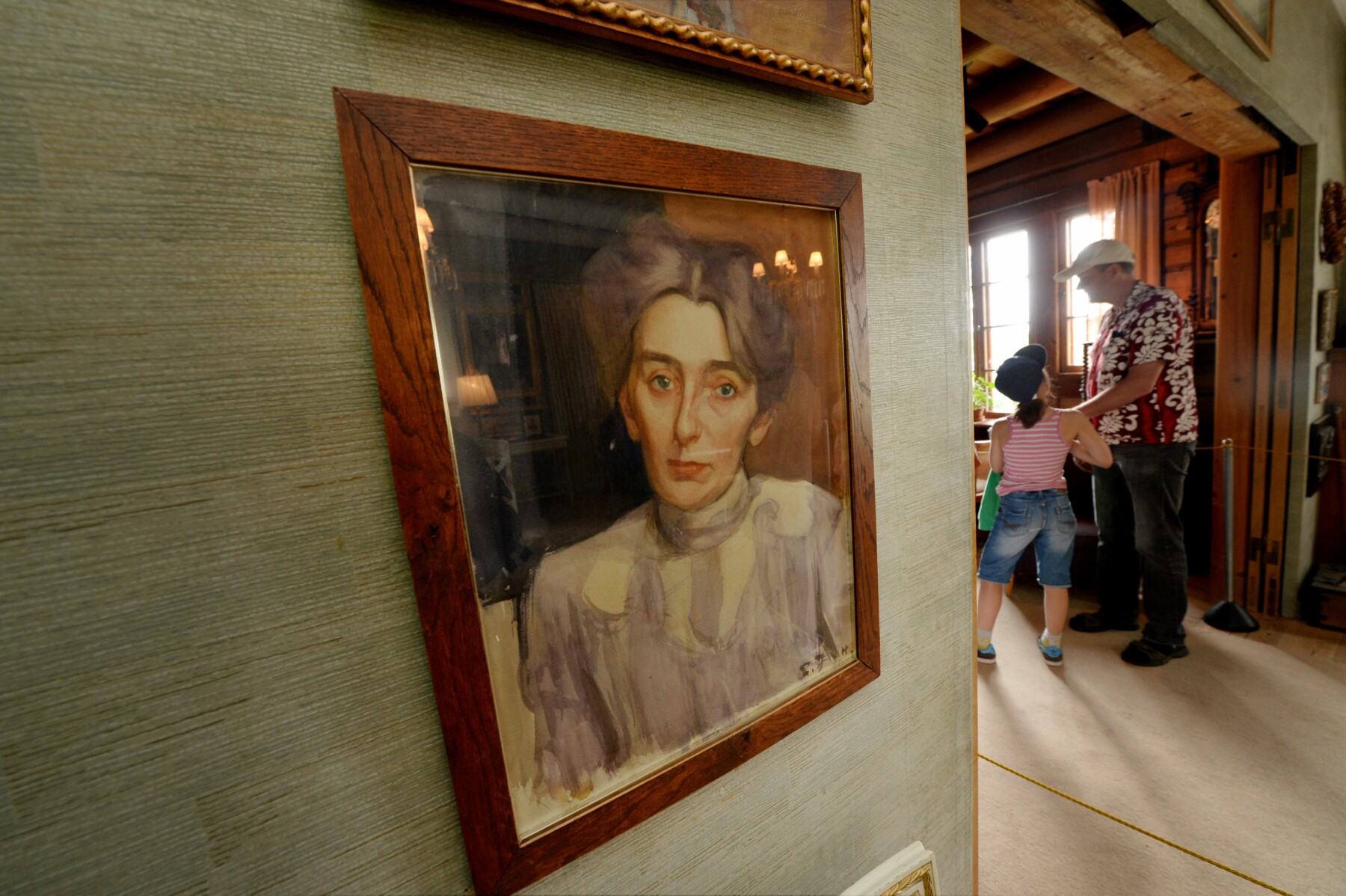 A painting hanging in a house shows a woman’s face and shoulders.