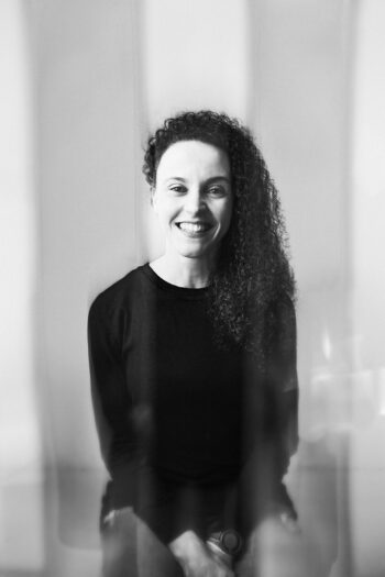 In a portrait photo, a sitting woman looks into the camera.