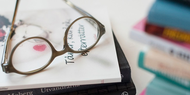 Eine Brille liegt auf einem Stapel von Büchern.