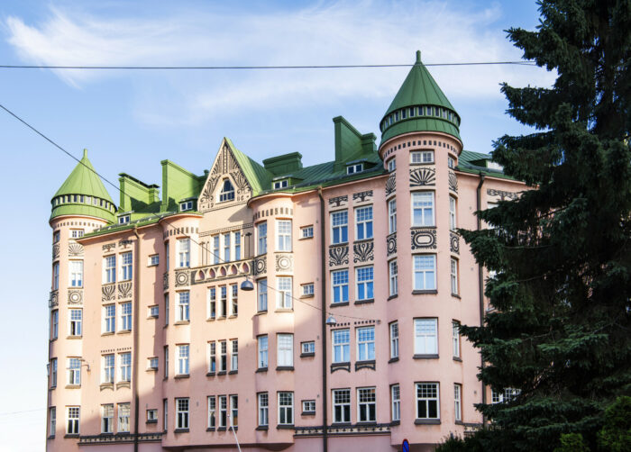 Uma variedade de edifícios residenciais em Helsinque, a maioria com fachadas suaves e detalhes ornamentais como torres, sacadas, frontões e janelas salientes que lembram a arquitetura de castelos.