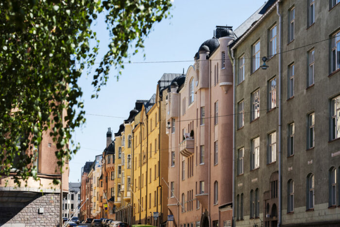 Varios edificios residenciales de Helsinki, la mayoría con fachadas lisas y detalles ornamentales como torreones, balcones, gabletes y ventanales que recuerdan a la arquitectura de los antiguos castillos.