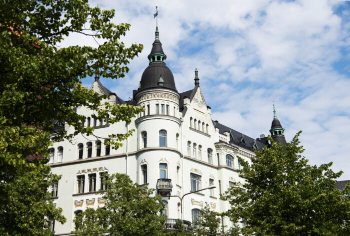 Ces photos présentent plusieurs vues d'un bâtiment à la façade ouvragée, dont un gros plan sur un pignon doté de motifs ornementaux semblant former un visage avec une ligne droite en guise de bouche.