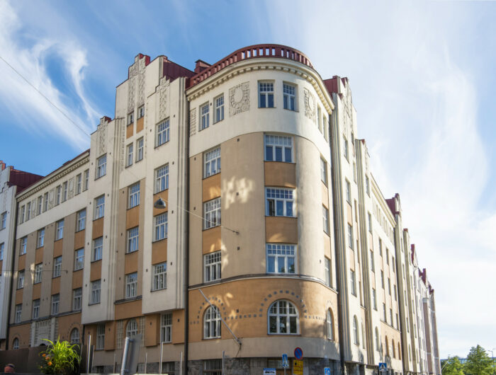 Uma variedade de edifícios residenciais em Helsinque, a maioria com fachadas suaves e detalhes ornamentais como torres, sacadas, frontões e janelas salientes que lembram a arquitetura de castelos.