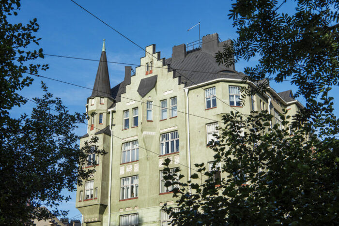 Varios edificios residenciales de Helsinki, la mayoría con fachadas lisas y detalles ornamentales como torreones, balcones, gabletes y ventanales que recuerdan a la arquitectura de los antiguos castillos.