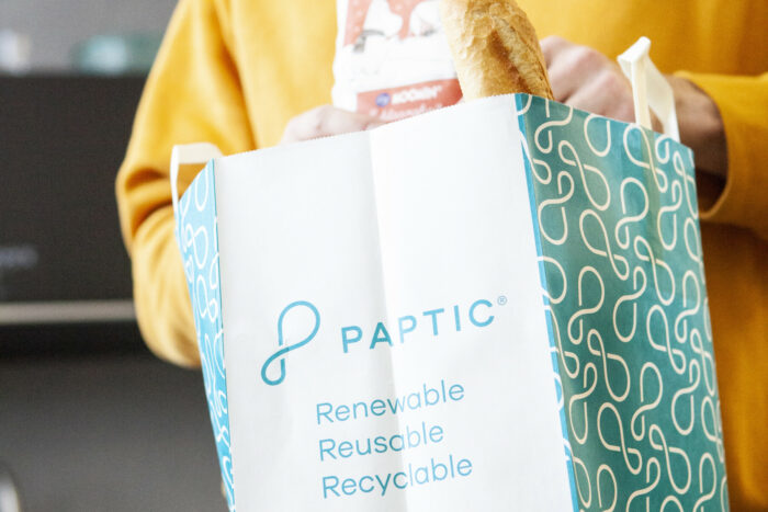 A person is holding a shopping bag full of groceries.