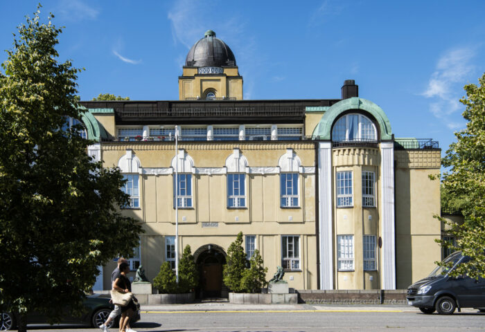 Varios edificios residenciales de Helsinki, la mayoría con fachadas lisas y detalles ornamentales como torreones, balcones, gabletes y ventanales que recuerdan a la arquitectura de los antiguos castillos.