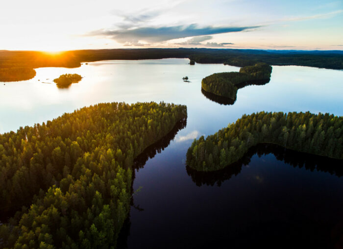 Vista aérea de un lago en calma en el que se aprecian varias penínsulas cubiertas de bosque.