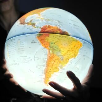 A person is holding an illuminated globe in their hands.