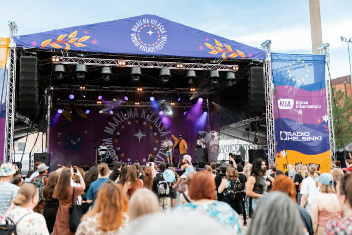 A bunch of people are standing in front of a stage listening to a concert.