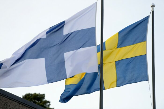 Les drapeaux finlandais et suédois hissés sur leur mât respectif flottent côte à côte au vent. 