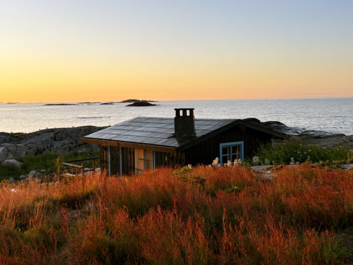 Vista del atardecer sobre una cabaña a la orilla del mar.