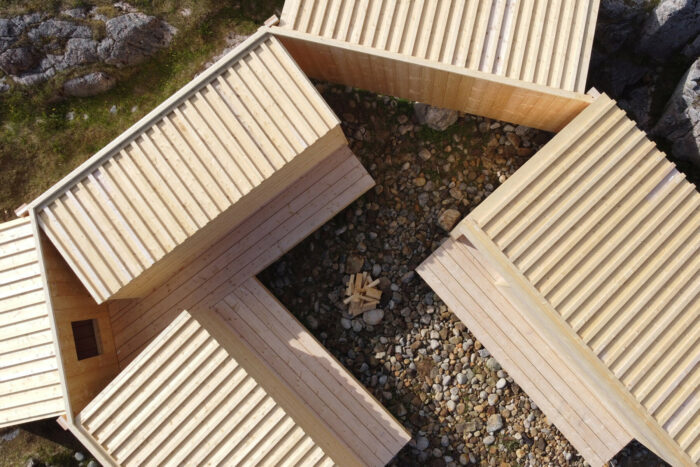 Imagen aérea de varios edificios de madera construidos sobre un terreno rocoso.