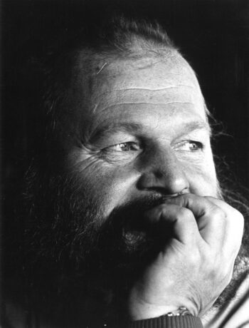 In a black-and-white photo, a man rests his chin on his hand.