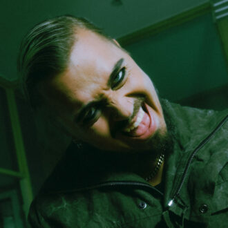 A man with kohl on his eyes grimaces at the camera.