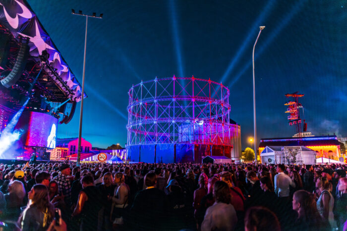A large crowd enjoying festival music in an urban setting at night.