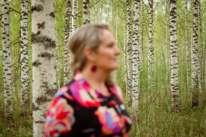 A woman standing in a birch forest.