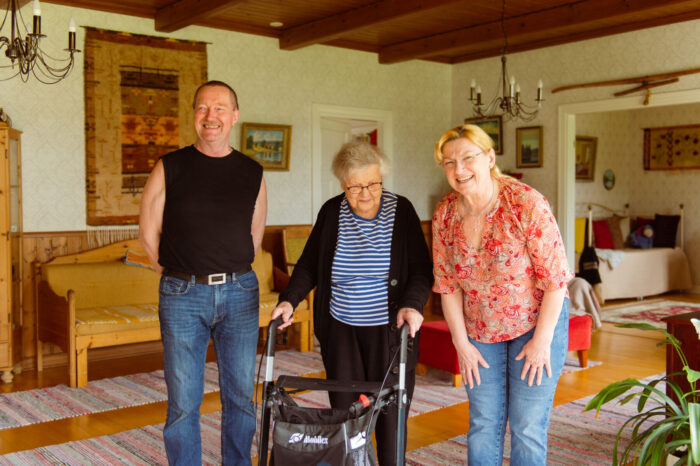 A man and two women smiling in a cosy living room.