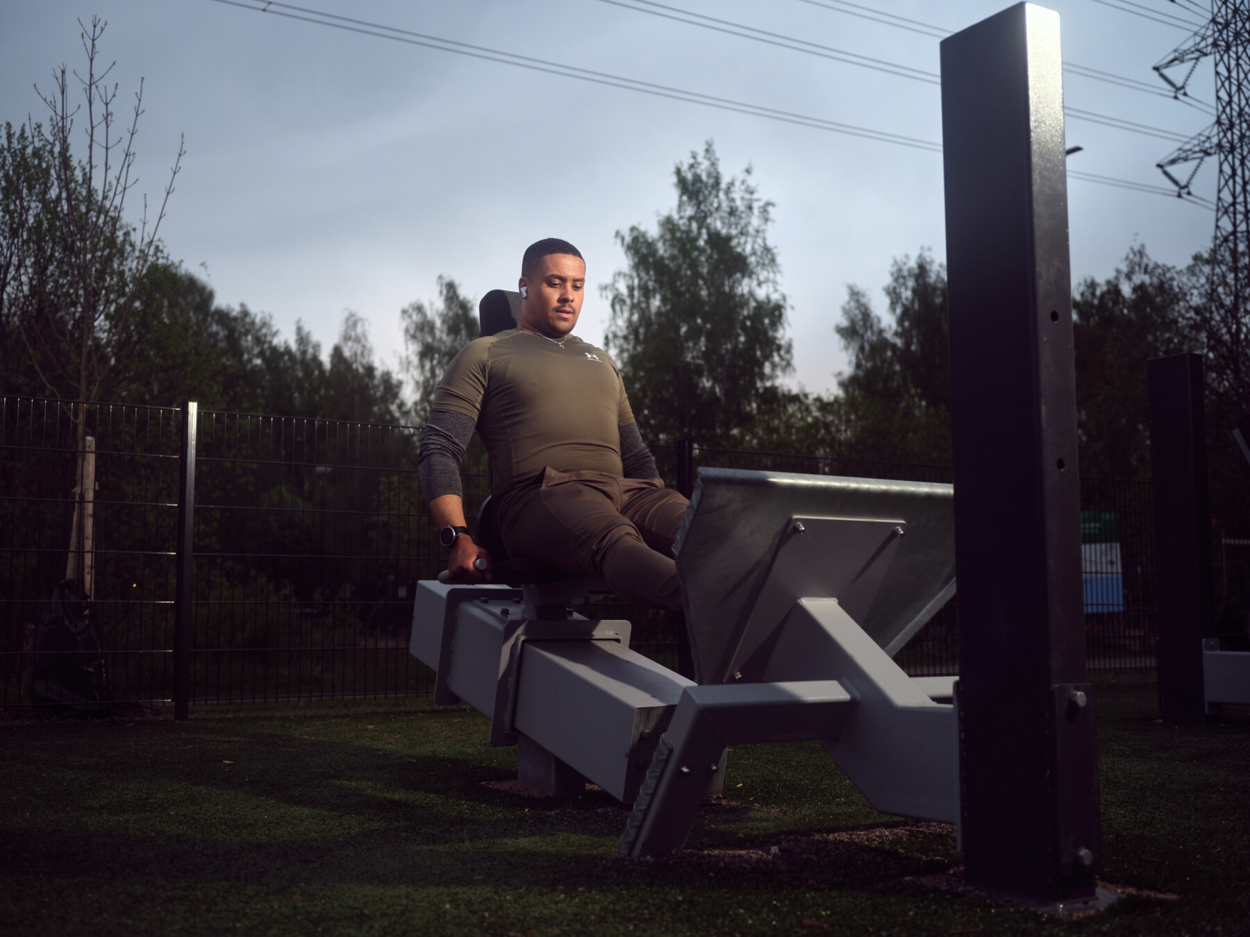 A man performs a leg press at an outdoor gym.