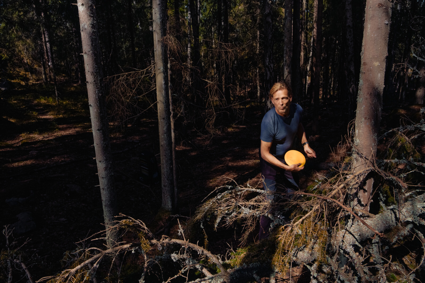 A man plays disc golf in a springtime forest.