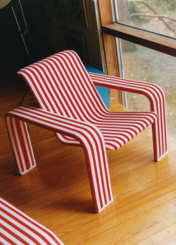 A modern red-and-white striped chair positioned near a window.