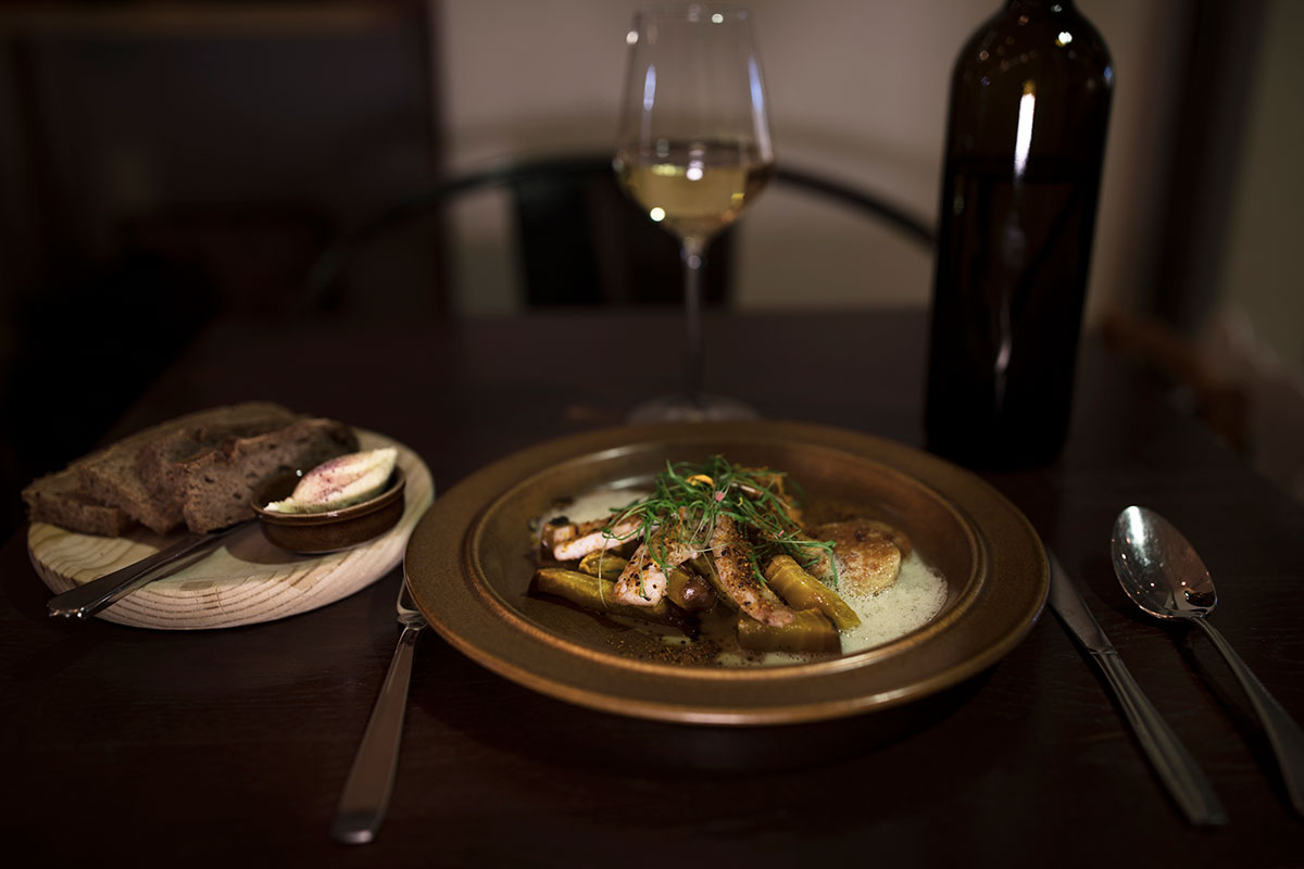 Um prato principal com pão e vinho branco servido em uma mesa de restaurante.