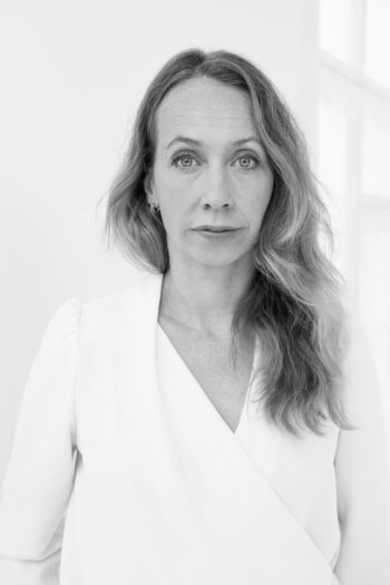 Black and white portrait of a woman looking directly at the camera with a calm, neutral expression.