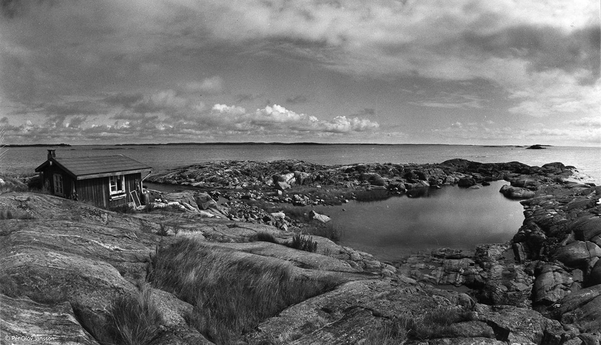 A rugged island shoreline with a small cottage on the left.