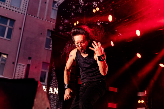 A man yells as he plays an imaginary guitar on stage.