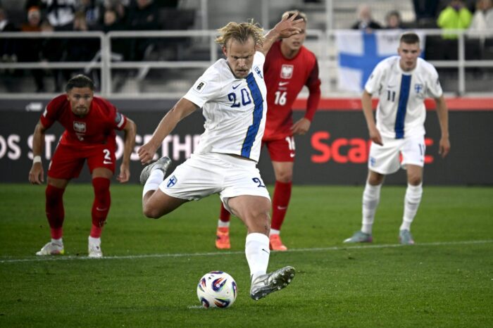A male footballer kicks the ball on a football pitch.