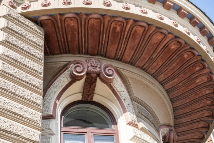 Sculptures of mythological creatures appear above the windows and doorways of a 19th-century renaissance revival building.
