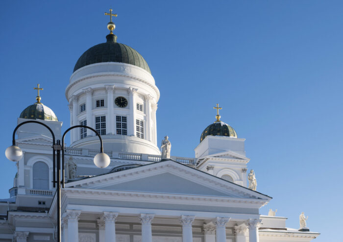 A large white church on a terrace at the top of a wide set of steps features statues of people holding various objects.