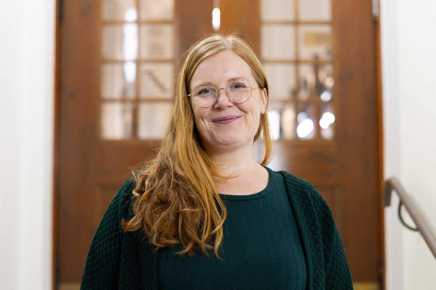 A woman poses in front of an old-fashioned wooden door.