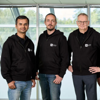 Five men in matching black hoodies stand in a row, smiling for the camera.