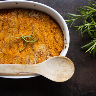 ملعقة خشبية موضوعة فوق صينية فرن تحتوي على وصفة برتقالية مصنوعة في الفرن.