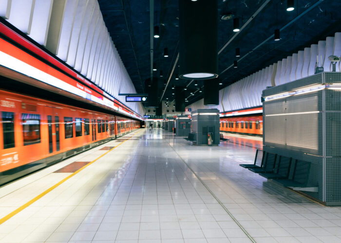  Koivusaari metro station shows a wide tiled platform with orange trains and modern lighting in a clean underground space.
