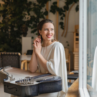 Päivi Kujanen posa sonriente junto a su kantele en el estudio de Alvar Aalto, en Helsinki.