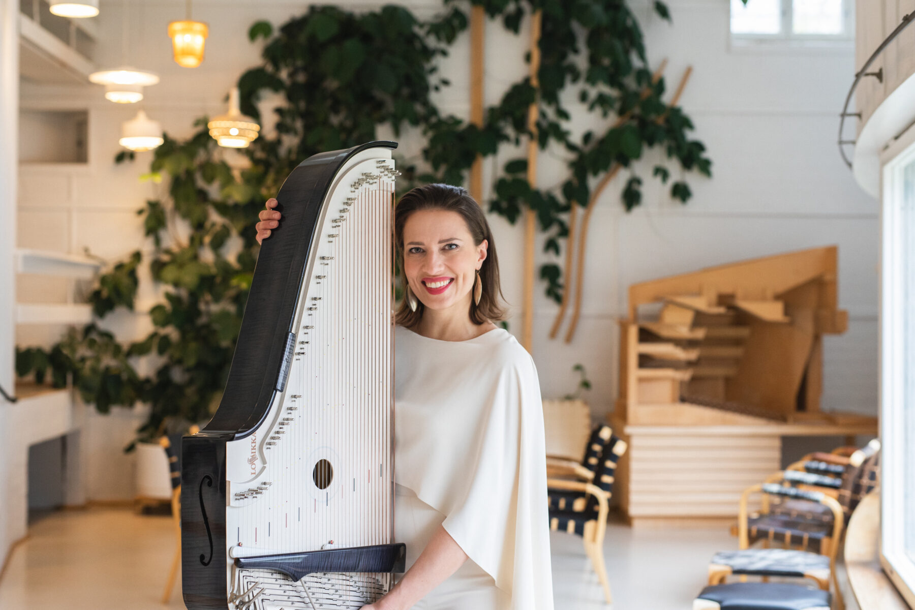 Päivi Kujanen smiles holding her concert kantele at the Alvar Aalto Studio in Helsinki.