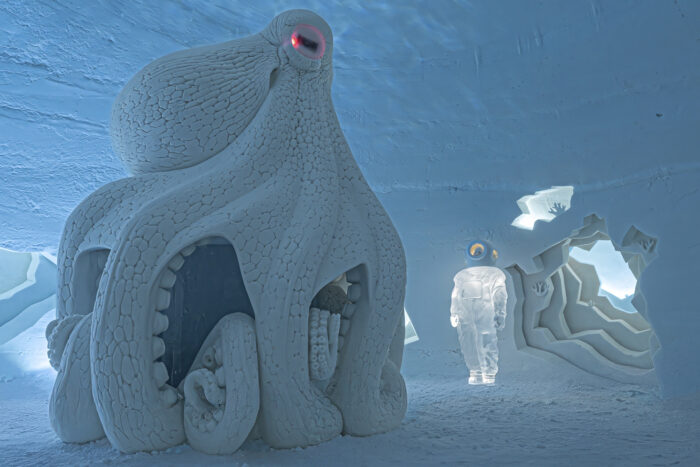 An enormous-looking statue of an octopus made out of snow stands in a room whose walls also appear to be made of snow and ice.