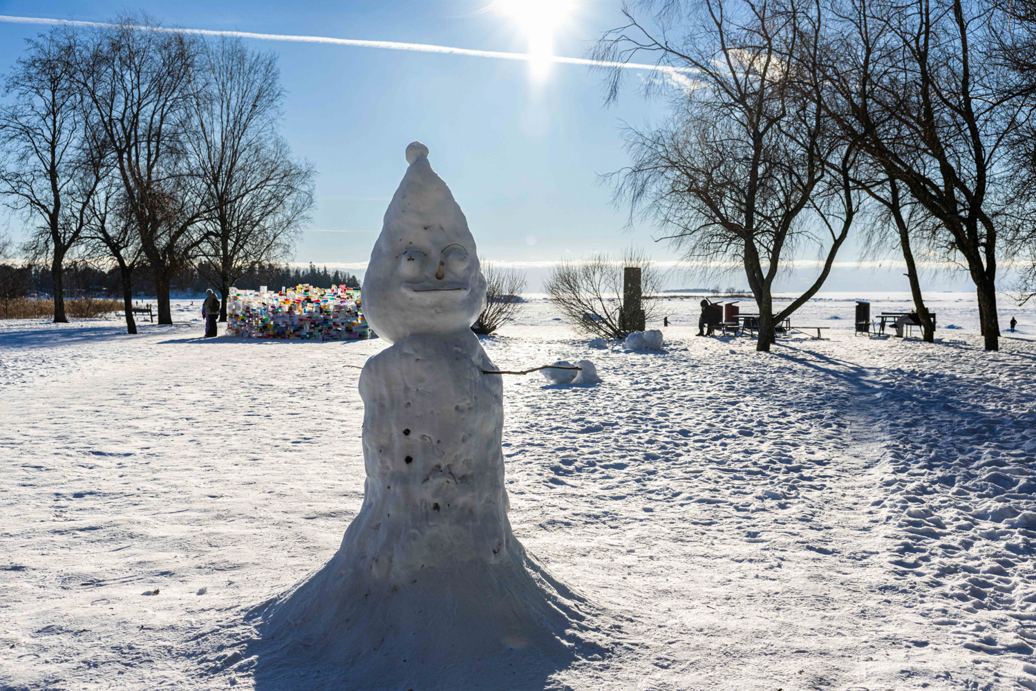 A snowperson with a pointy snow hat stands in a clearing near the shore in the Helsinki neighbourhood of Lauttasaari.