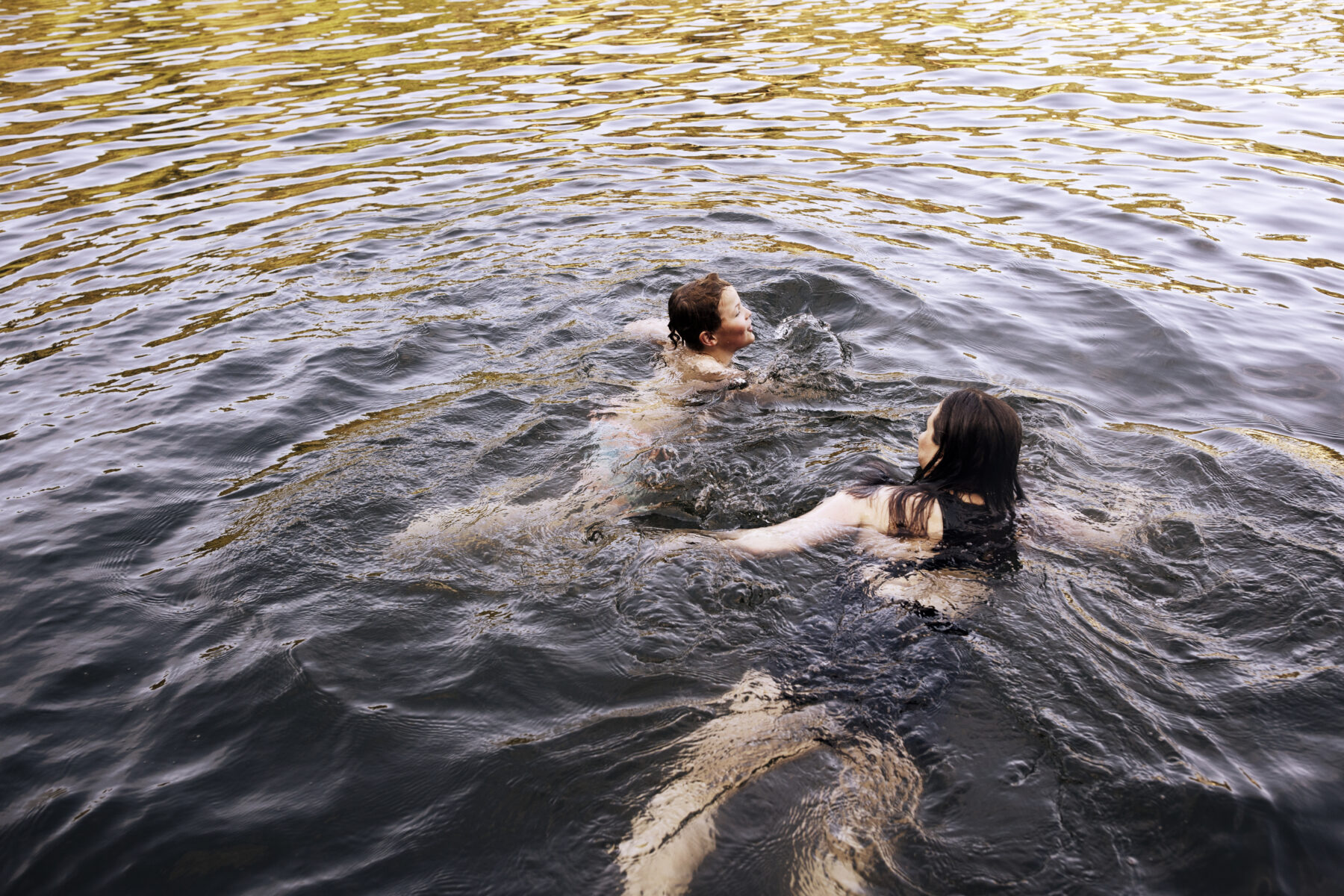Two people, including Saara Kotiranta, swim in a lake.